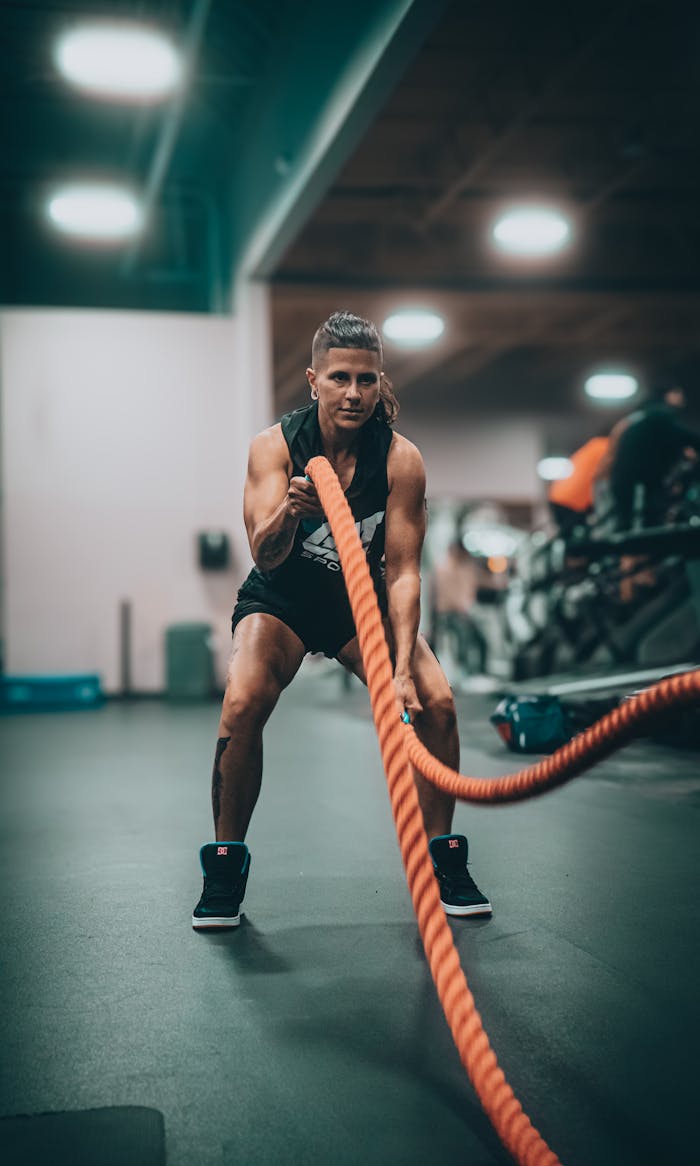 Athletic person performing an intense battle rope exercise in a modern gym setting.