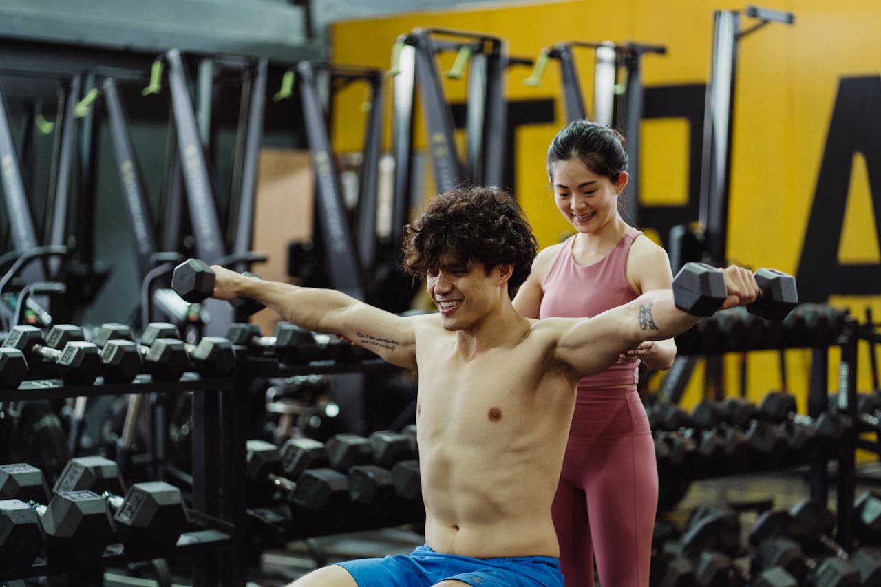 why-choose-us Man lifting weights with guidance from woman in modern gym setting.